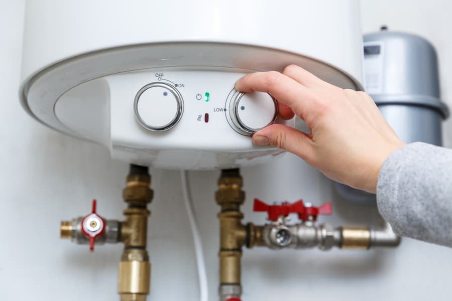 Female Hand Puts Thermostat Of Electric Water Heater In Low Low Power Consumption Mode