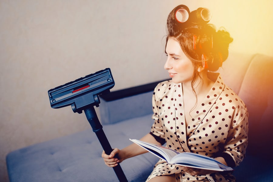 Girl With Curls On The Head Of A Hair Curler Holds A Plunger And A Brush From A Vacuum Cleaner