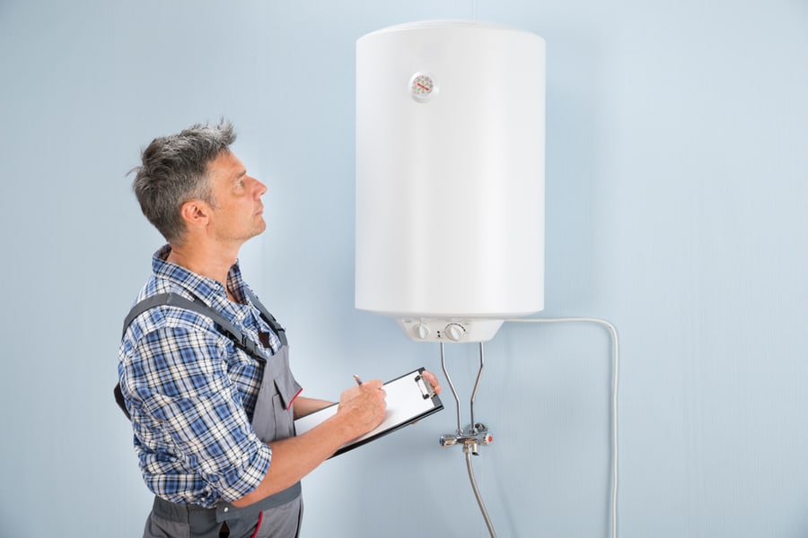 Male Plumber Holding Clipboard Looking At Electric Boiler
