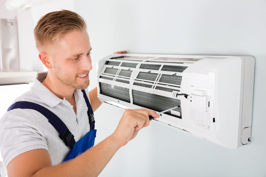 Male Technician Repairing Air Conditioner With Screwdriver