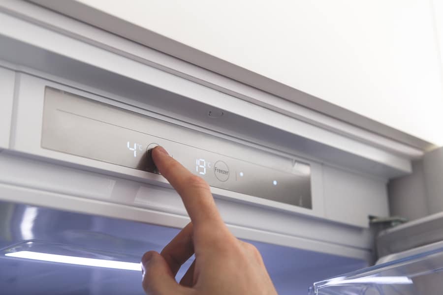 Man Adjusting The Temperature Of His Fridge