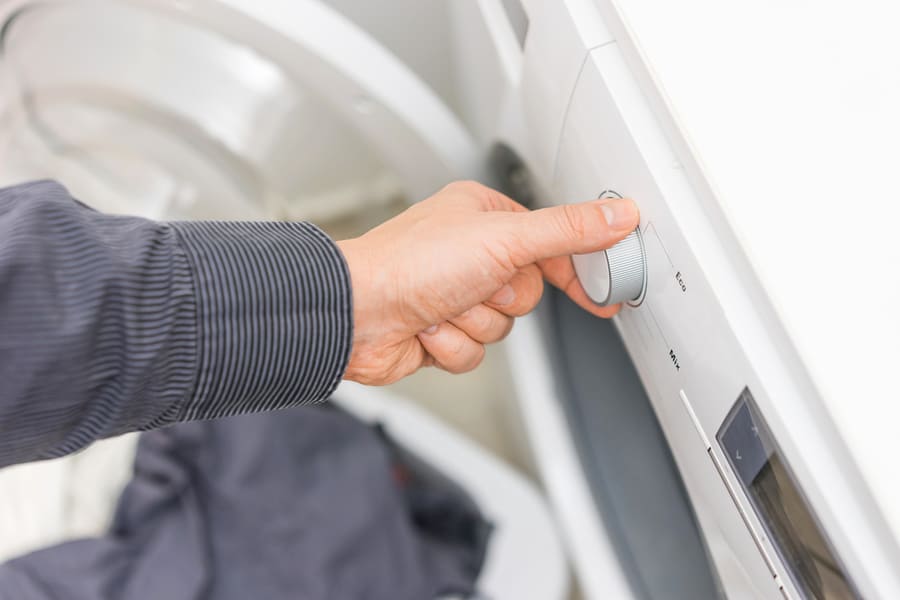 Man Is Choosing Eco Program On The Washing Machine,Concept Of Electricity Savings