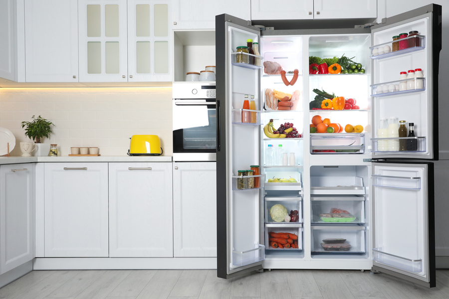Open Refrigerator Filled With Food In Kitchen.