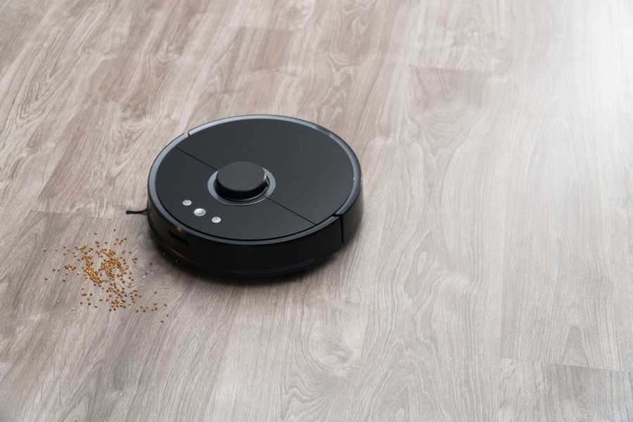 Robot Vacuum Cleaner Black On The Floor Is Cleaning, Gray Laminate.