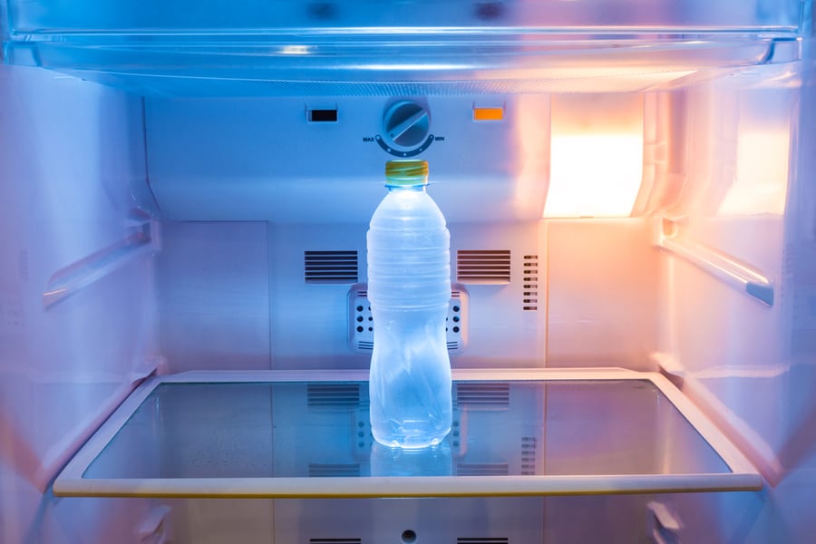 Single Cold Water Bottle On A Shelf In Refrigerator With Warm Light On