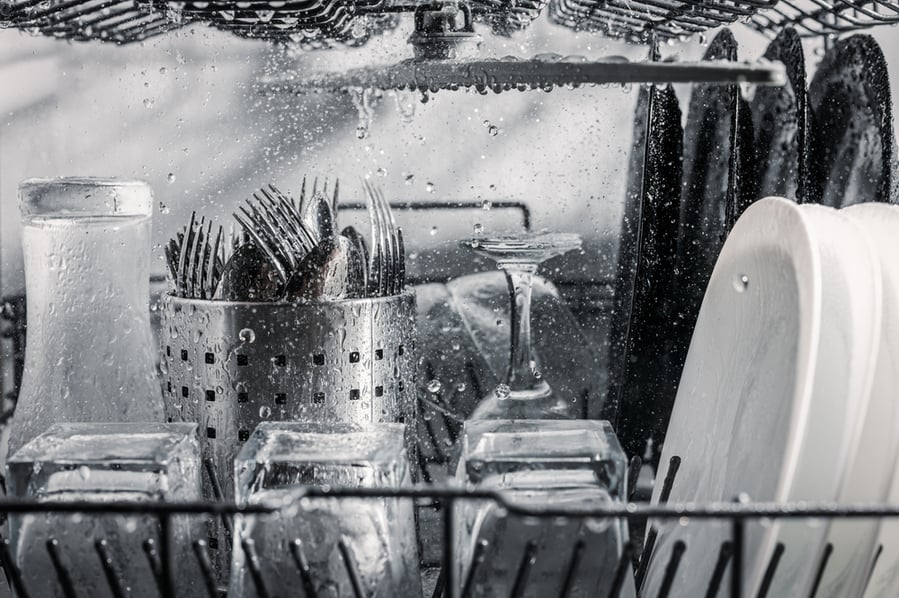 Transparent And Black And White Dishes As Well As Cutlery And Glasses Are Washed In The Dishwasher.