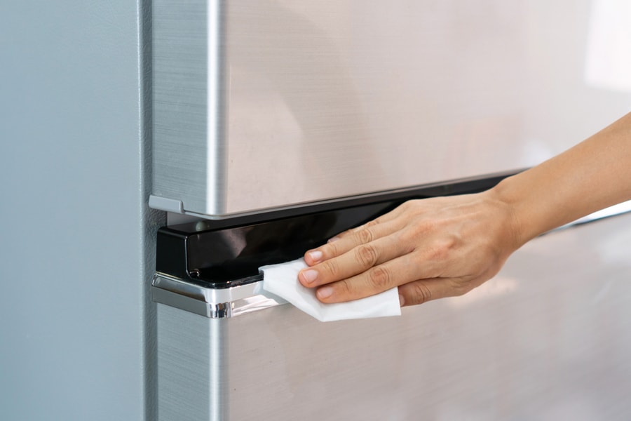 Woman Cleaning Stainless Steel Refrigerator With Wet Wipe Tissue At Home