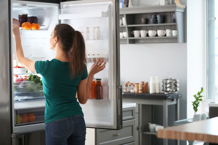 Woman Taking Food Out Of Fridge At Home