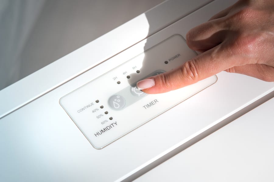 Woman Turning On Air Dryer, Purifier, Dehumidifier Or Humidity Indicator