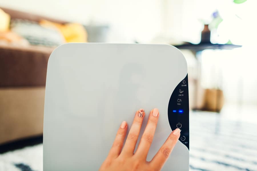 Woman Turns Dehumidifier On Using Touch Panel At Home. Modern Airdryer Device For Cleaning Air. Close Up