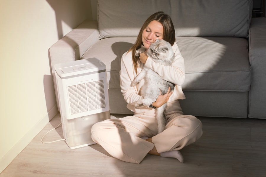 Woman With Her Cat Breathing Fresh Air At Home.