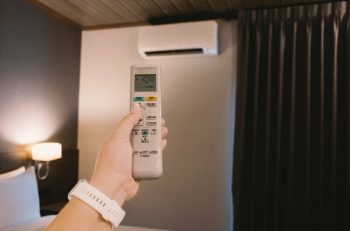 Woman'S Hand Holding Remote Airconditioner In Bedroom At Night