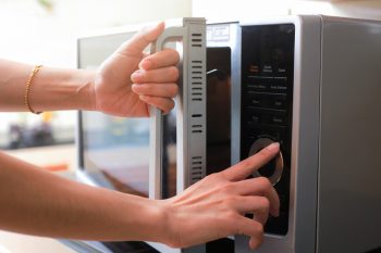Woman'S Hands Closing Microwave Oven Door And Preparing Food In Microwave