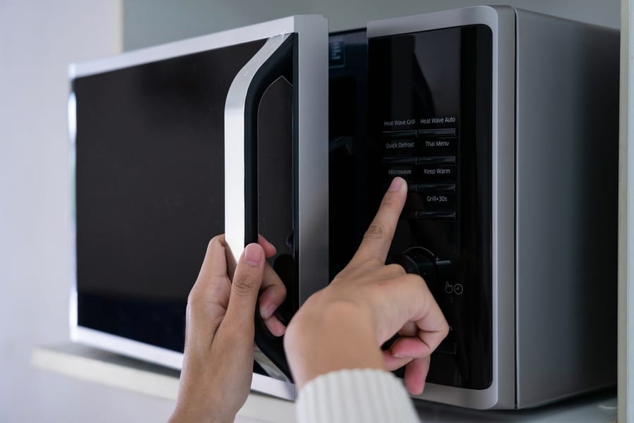 Woman's Hands Closing The Microwave Oven Door And Preparing Food In Microwave