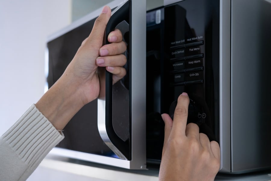 Woman's Hands Closing The Microwave Oven Door