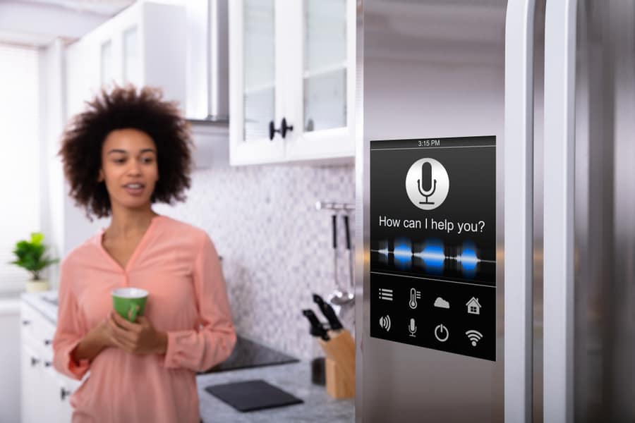 Young Woman Holding Green Coffee In Hand Looking At Refrigerator