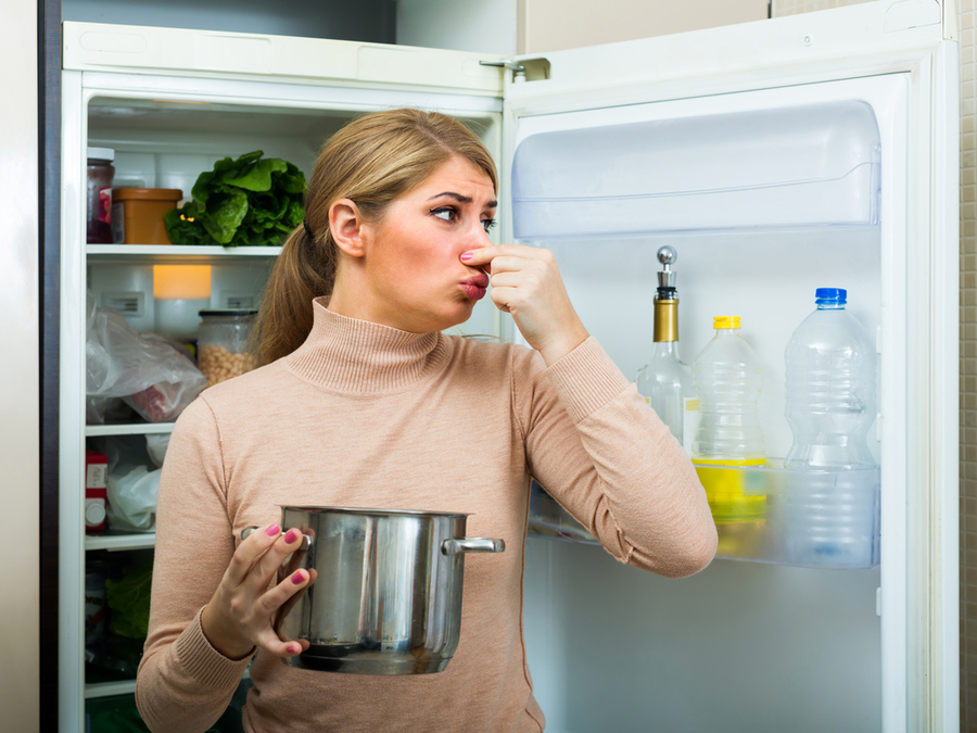 Young Woman Smelling Foul Smell Of Food From Casserole At Kitchen