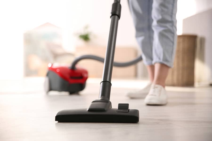 Young Woman Using Vacuum Cleaner At Home.
