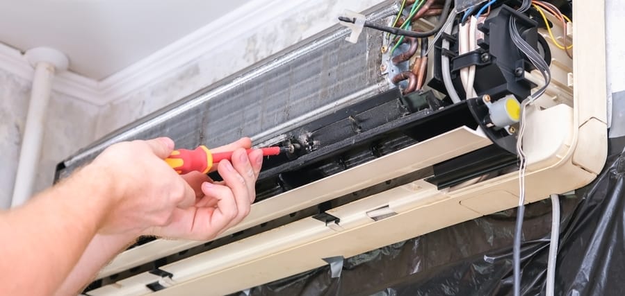 A Man Disassembles An Air Conditioner For Repair And Cleaning