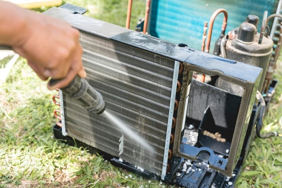 A Man Washes And Cleans The Evaporator Coil Of An Old Window Type Air Conditioning Unit