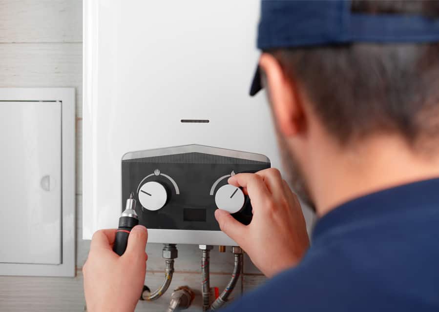 A Specialist In A Uniform Repairs A Gas Water Heater Or Boiler