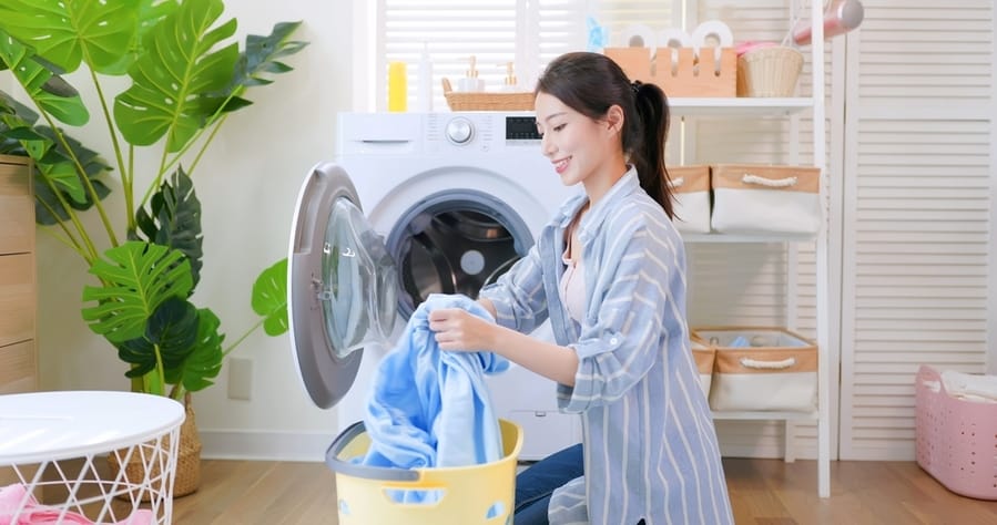 Asian Housewife Put Clothes Into Washing Machine Happily At Home
