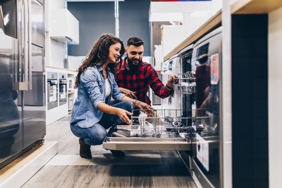Beautiful And Happy Young Couple Buying Dishwasher In Modern Appliances Store