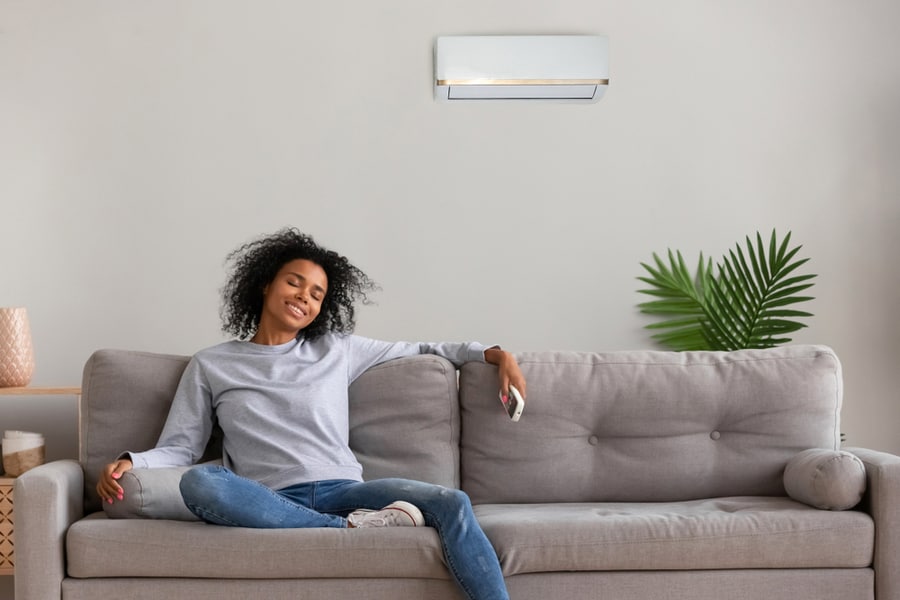 Calm African American Woman Sit On Couch Relaxing Under Air Conditioner