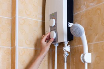 Close-Up Of Hands Setting The Temperature Of Water In Electric Boiler In The Shower Room