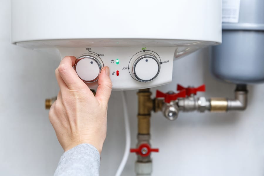 Female Hand Turning On Electric Water Heater
