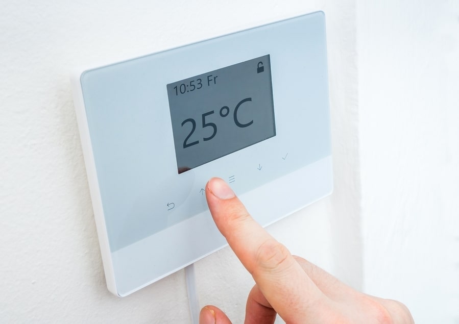 Hand Is Adjusting Temperature In Room On Digital Central Thermostat Control
