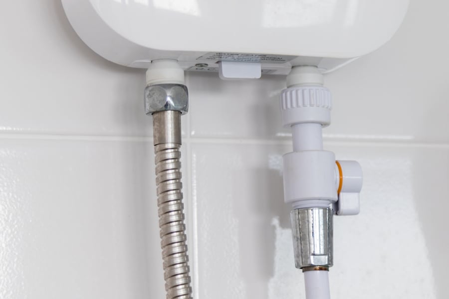 Instant Tankless Electric Water Heater Installed On White Tile Wall