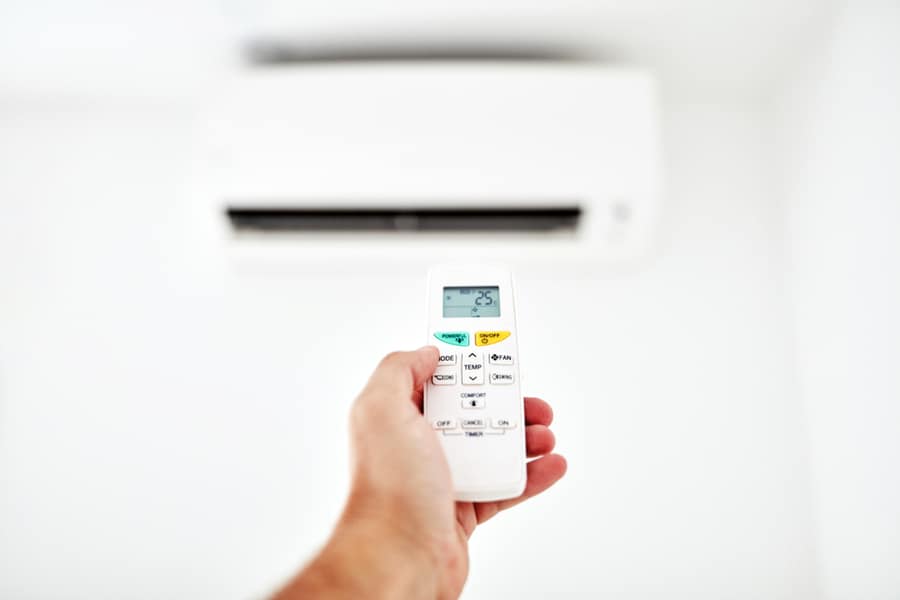 Modern Air Conditioner Unit With A Hand Holding A Remote
