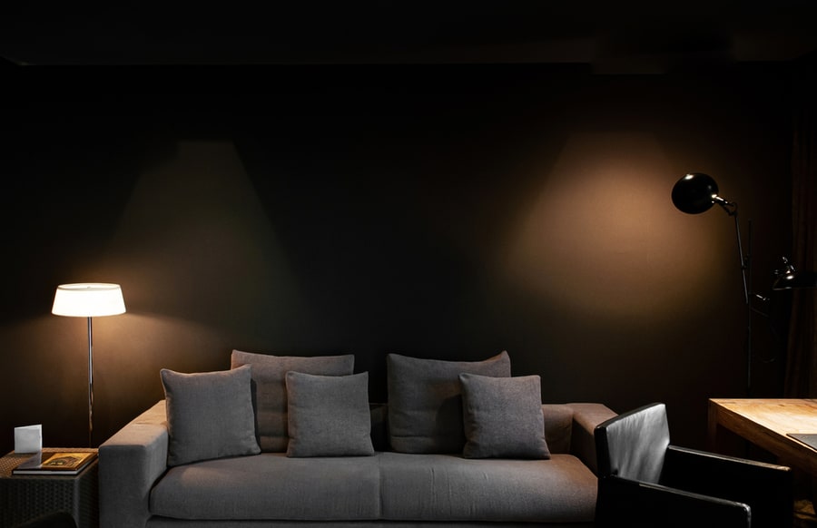 Modern Dark Tone Living Room With Gray Fabric Sofa Couch And Spot Lighting On Black Wall