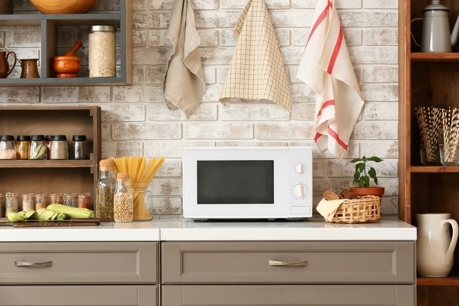 Modern Microwave Oven On Counter Near Light Brick Wall In Stylish Kitchen