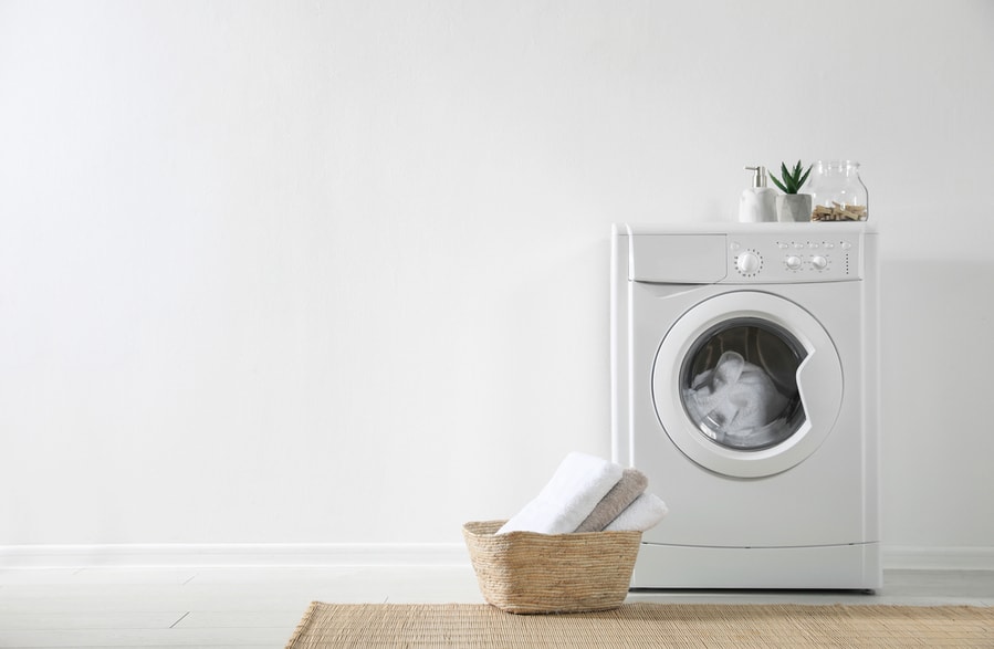 Modern Washing Machine And Laundry Basket Near White Wall Indoors
