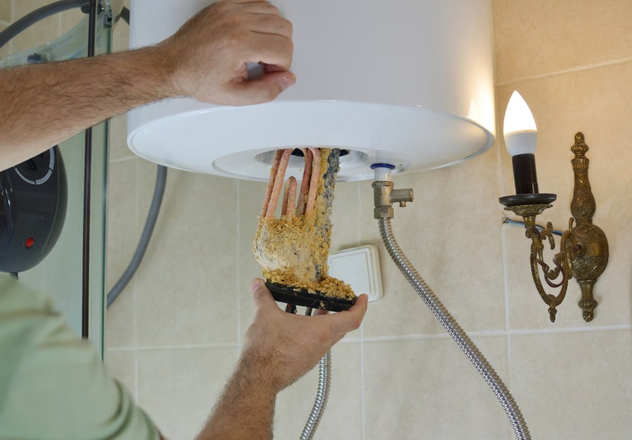 Plumber Taking Out An Old Water Heater With Scale Deposition From A Boiler In A Bathroom