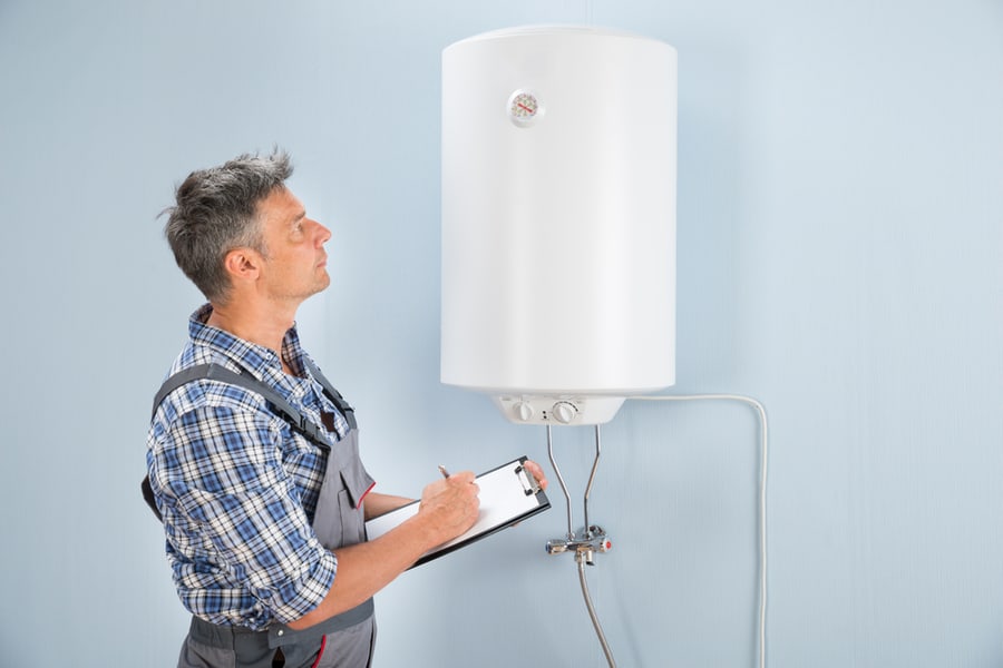 Portrait Of Mid-Adult Male Plumber Holding Clipboard Looking At Electric Boiler