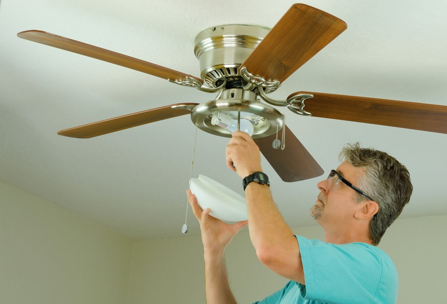 Professional Doing Ceiling Fan Repair Work With The Glass Cover Removed