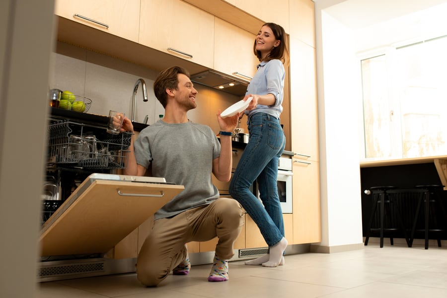 Smiling Male Is Putting Dishes Into Dishwasher