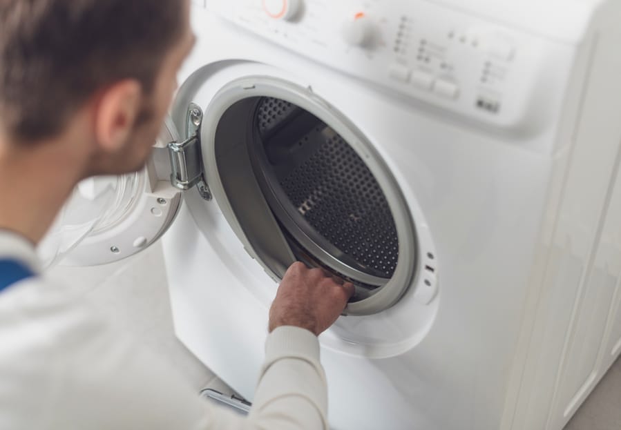 Technician Repairing A Washing Machine At Home, He Is Checking The Gasket