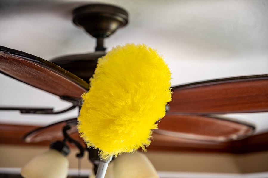 Using A Wand Feather Duster To Remove And Clean Dust From A Ceiling Fan