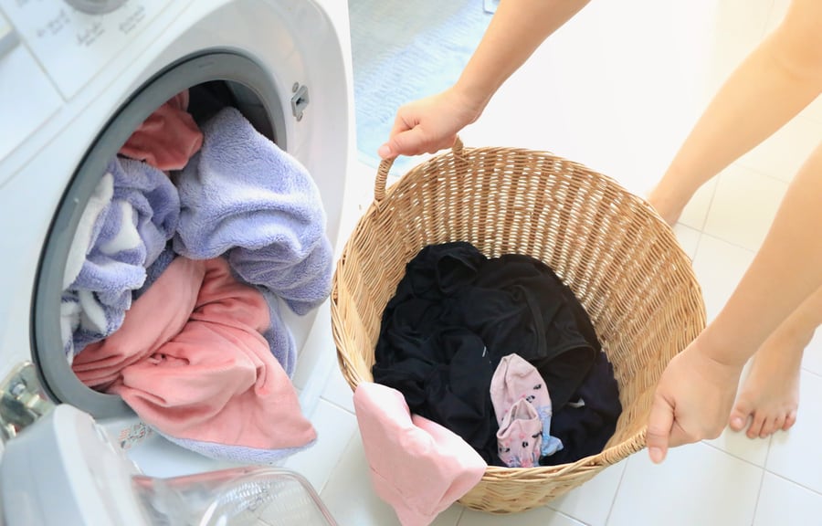 Woman Carried A Laundry Basket In The Washing Machine And The Washing Machine Is Full Of Clothes That Need Cleaning.