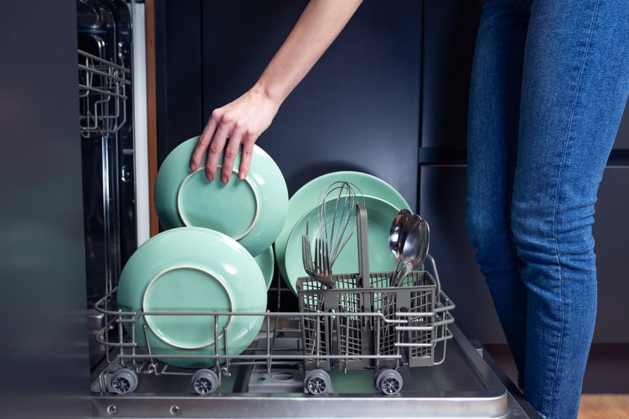 Woman Doing Dishes In A Modern Kitchen With Dishwasher