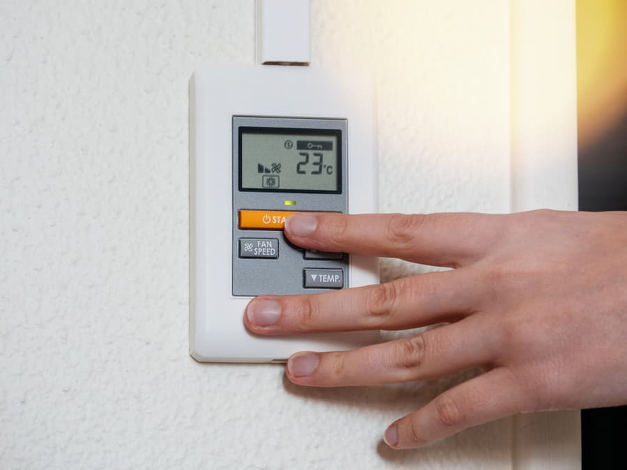 Woman Hand Adjusting A Wall Mounted Thermostat Temperature For The Room Ac Air Conditioning