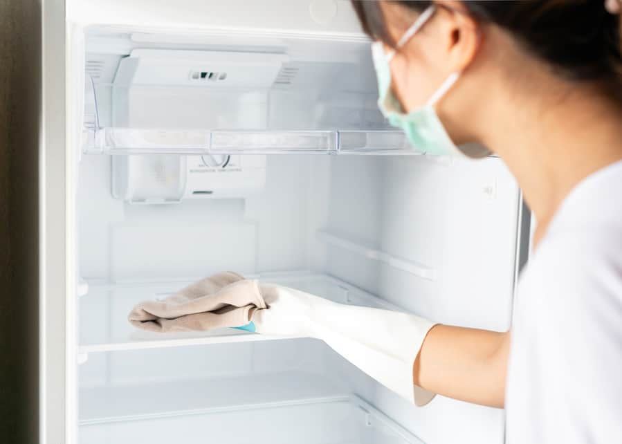 Woman In White Rubber Protective Glove Cleaning White Empty Refrigerator With Rag