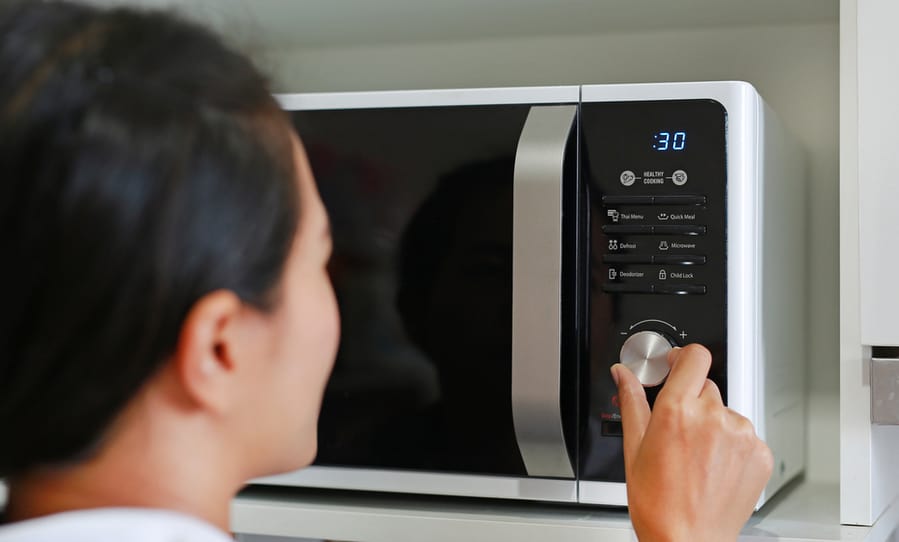 Woman Using Microwave Oven At Home