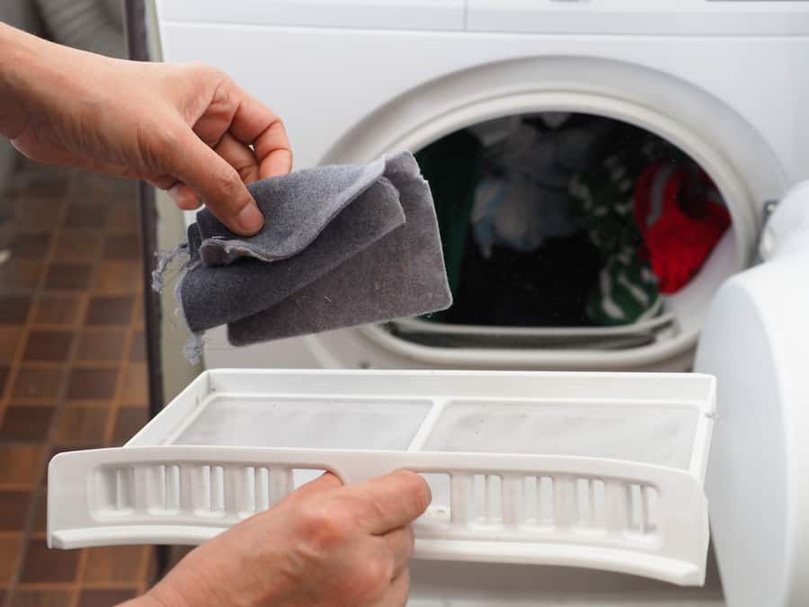 Woman’s Hand Removing Lint From Fluff Filter Of The Tumble Dryer
