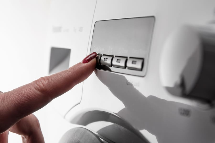 Woman's Index Finger With Nail Polish Pushing Start Button On White Modern Washing Machine