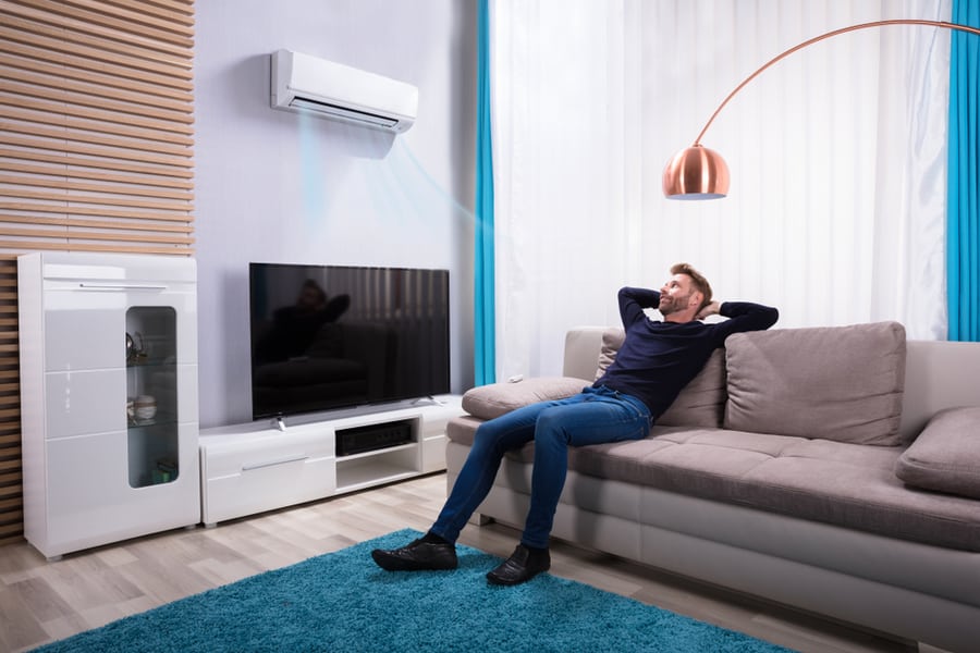 Young Man Relaxing On Sofa Near Television At Home